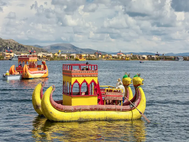 Barco de totora navegando no Lago Titicaca em Puno, conduzido por um morador local.