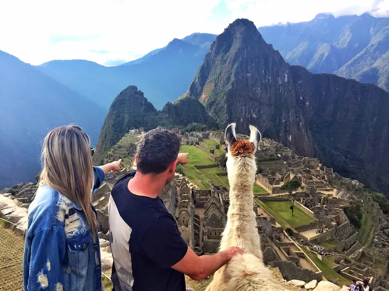 Casal de turistas brasileiros com uma lhama admirando Machu Picchu no tour de 5 dias em Cusco