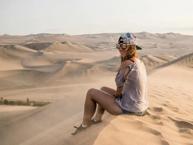 Turista no deserto usando chapéu e protetor solar em Ica