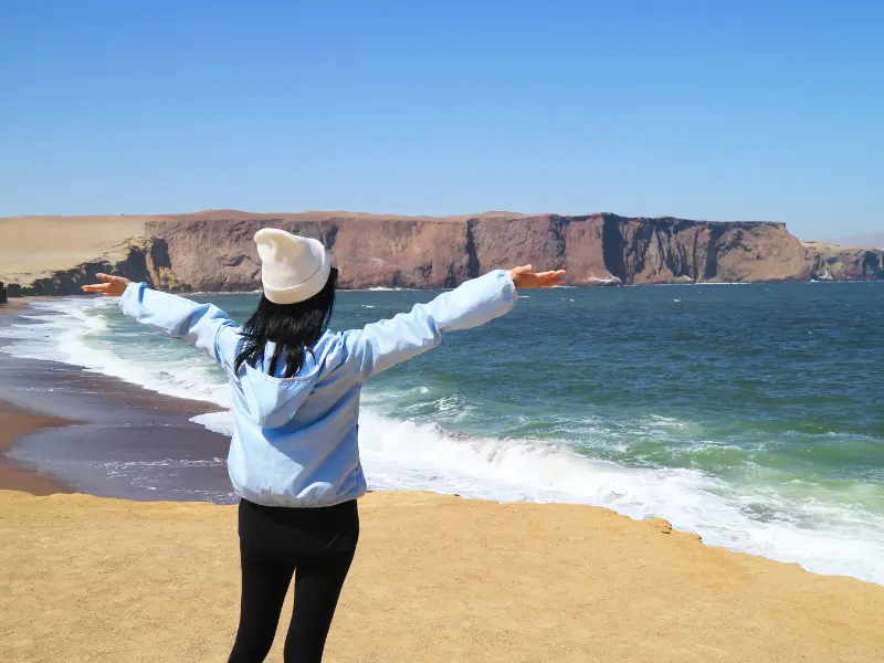 Turista com casaco em Paracas devido ao vento